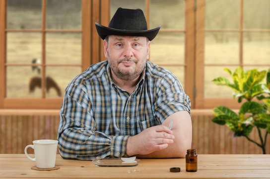 Mature farmer in black hat holds syringe for injection