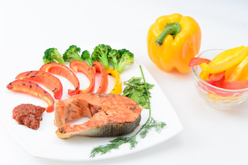 Grilled red fish with sauce, broccoli, parsley and dill  on a white plate
