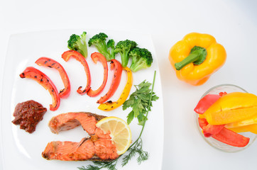 Grilled red fish with sauce, broccoli, parsley and dill  on a white plate