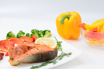 Grilled red fish with sauce, broccoli, parsley and dill  on a white plate