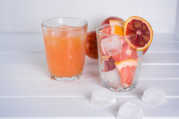 Full glass of grapefruit juice and glass of sliced fruit