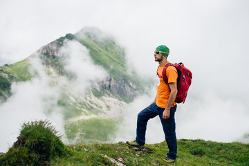 Young sports guy with a backpack hiking in green mountains in Romania
