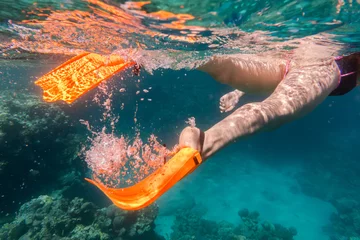 Rolgordijnen Girls legs in orange flippers underwater in sea near coral reef © Sergiy Bykhunenko