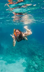Zelfklevend Fotobehang Meisje met zwemmasker duikt onder water in de buurt van koraalrif © Sergiy Bykhunenko