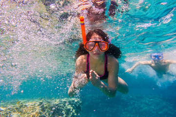 Girl and boy in swimming mask dive in Red sea near coral reef