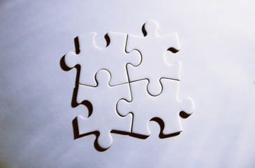 Vier zusammenhängende Puzzleteile auf weißem Grund