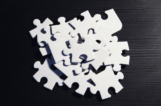 Haufen wei&szlig;er Puzzleteile auf schwarzem Grund