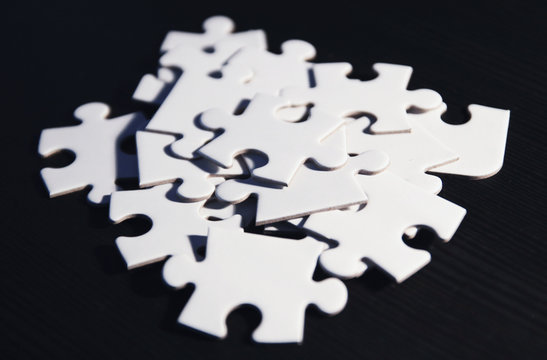 Haufen wei&szlig;er Puzzleteile auf schwarzem Grund