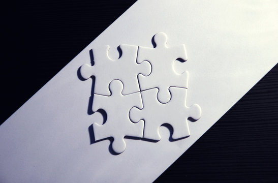 Vier zusammenh&auml;ngende Puzzleteile auf wei&szlig;/schwarzem Grund