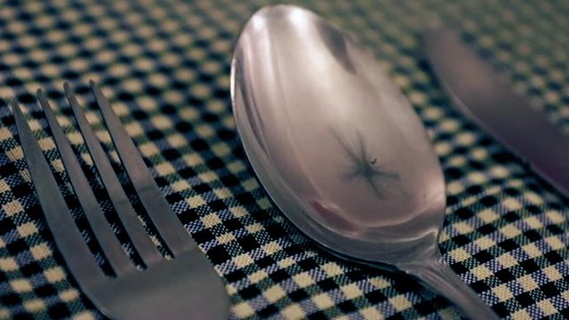 Reflection rotating fan in a spoon on a table with a tablecloth. Closeup cutlery on a restaurant table. 