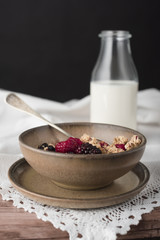 Cereal in brown bowl and milk in a bottle. 