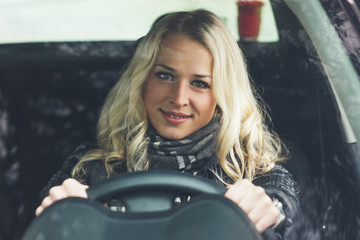 Obraz na płótnie Canvas Woman sitting in the car and keeps the wheel of a car
