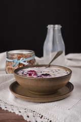 Cereal in brown bowl and milk in a bottle.