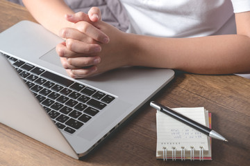 Young female clasping hands expect the result of her graduation or interview on laptop