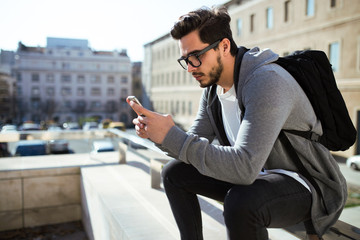 Handsome young man using his mobile phone in the street.
