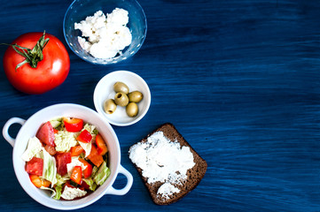 Salad of vegetables and feta cheese, the concept of a healthy diet. Bread and pastries, flour products. Top view on a dark background.