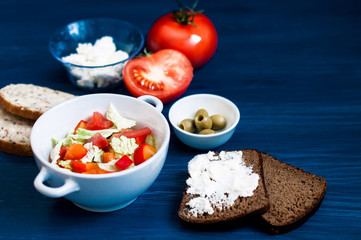 Salad of vegetables and feta cheese, the concept of a healthy diet. Bread and pastries, flour products. Top view on a dark background.