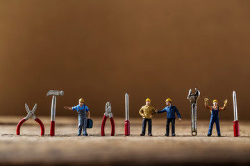 selective focus of miniature worker working with tool tools supplies and tiny home model  on wooden...
