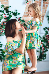 Mom and daughter in bright summer dresses are playing their hands