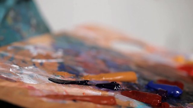 Young artist squeezes out brown paint on the palette