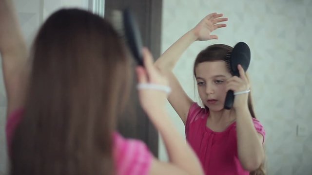 Little girl combs her hair