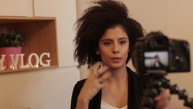 Young confident woman shooting vlog