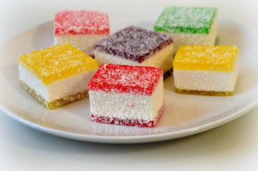 Разноцветный мармелад нарезанный кусочками на белой тарелке - вред сладкого 