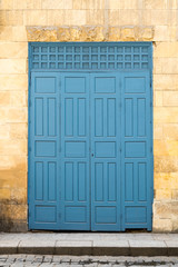 Vintage antique folding wooden decorated blue door over stone wall