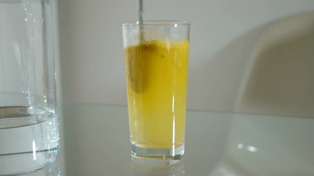 A spoonful of curry powder is added to the tall glass with pure water and mixed
