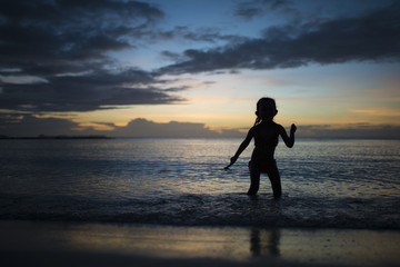 夕暮れのビーチで遊ぶ子供のシルエット