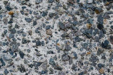 The surface texture of a cement wall with a piece of rock.