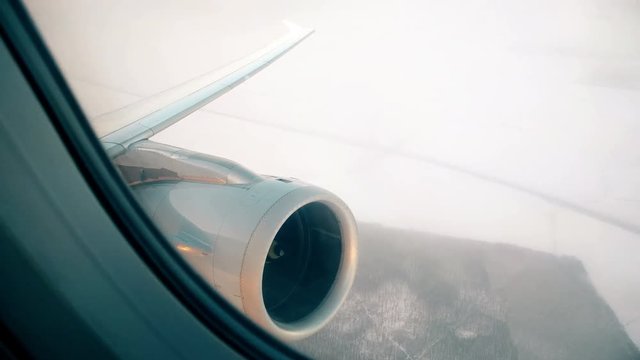 Footage of a passenger plane engine and wing, above a snowy field.