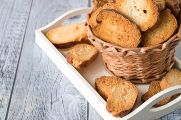 

 Homemade rusks.   Basket with homemade rusks on a white tray on a gray wooden table.