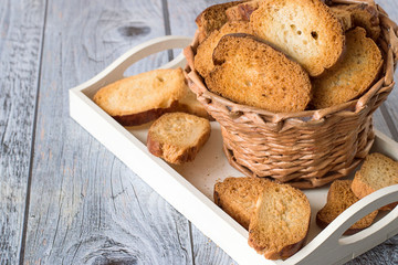 

 Homemade rusks.   Basket with homemade rusks on a white tray on a gray wooden table.