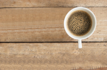 Cup of coffee on  table wood vintage background in top view.