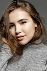 Naklejka premium Smiling cute girl with clear skin looking at the camera on gray background