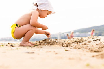 Baby playing on the sandy beach near the sea happy