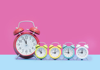 chain of cute colorful alarm clocks in front of wonderful pink background