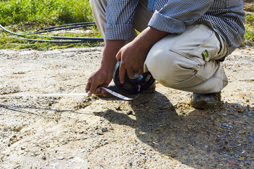 Close-up of a surveyor assistance measuring with measure tape at construction site
