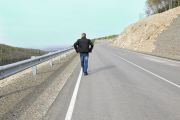 Fototapeta premium Man walking on a mountain road to his dream