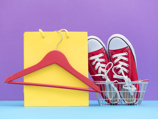 red gumshoes in shopping cart and shopping bag with hanger on the wonderful purple background