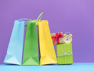 cute beautiful gifts, alarm clock and shopping bags on the wonderful purple background