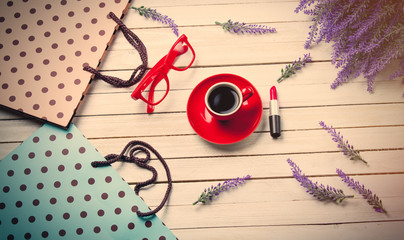 cup of coffee, glasses, lipstick, shopping bags and lavender on wooden white background