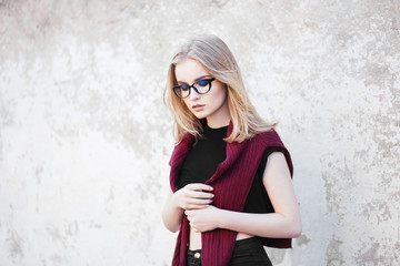 Portrait of a young girl with glasses and professional make up standing near a wall - 140218460