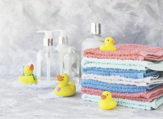 stack of towels with yellow rubber bath ducks on white marble background, space for text, selective focus