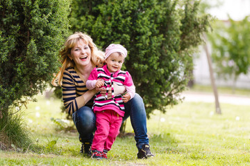 Fototapeta premium Mother and daughter laughing on the grass