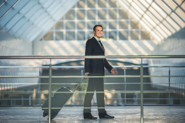 The happy man walk with a suitcase in the business center