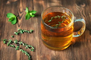 The Cup of tea on wooden background with mint leaves and thyme