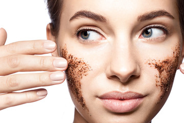 Close-up portrait of a beautiful woman with a coffee scrub on her face doing peeling skin isolated...