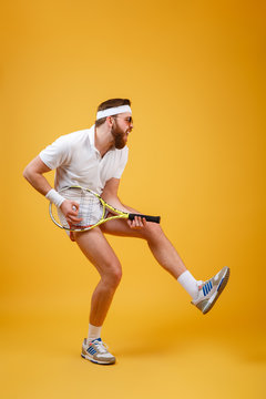 Vertical image of bearded sportsman playing on tennis racquet